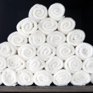 Pile of rolled white clean towel placed on the closet in the gym, ready to use for the work out person. Selective focus.
